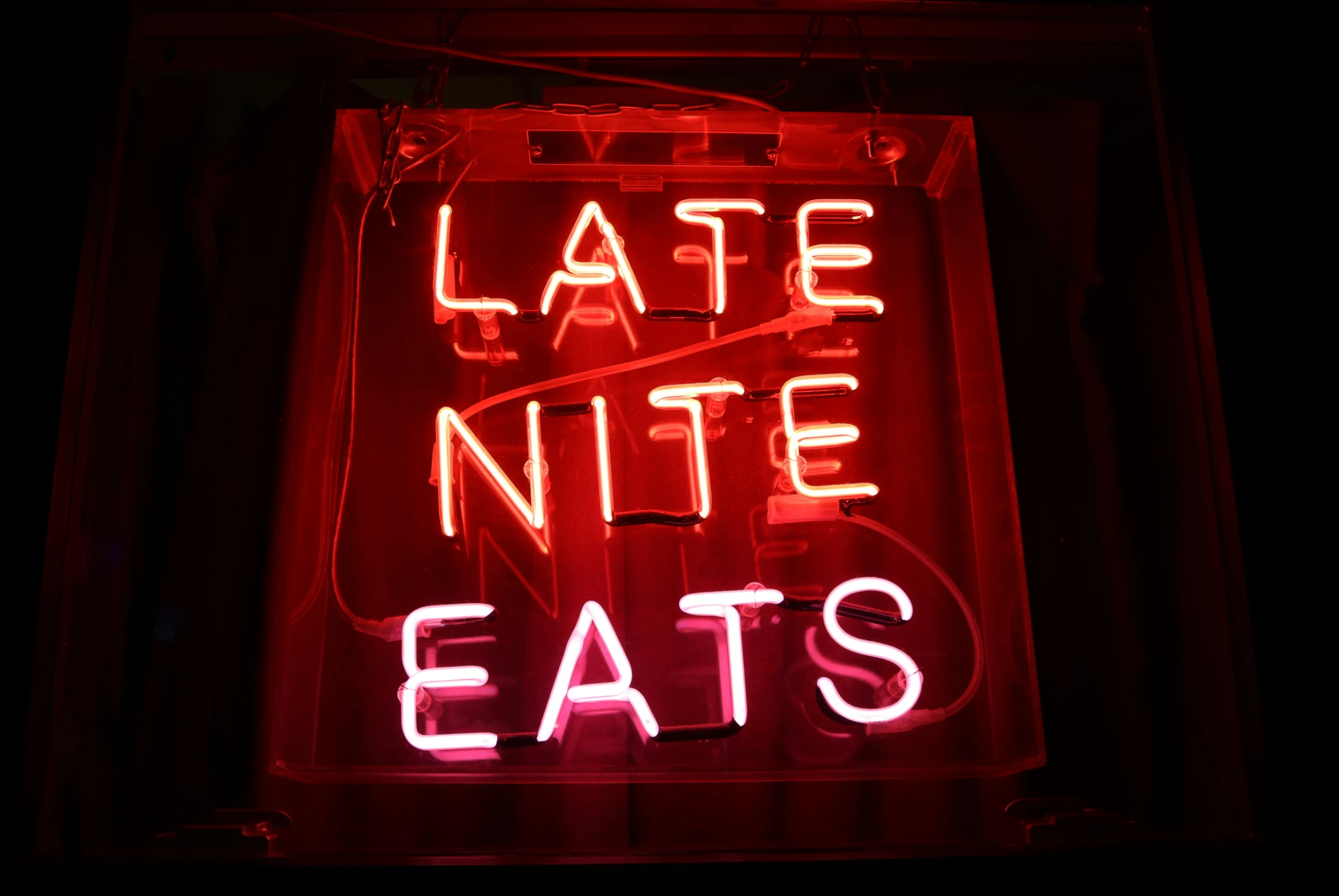 a lit neon sign sitting on the side of a building