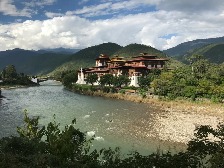 a scenic view of a building on a river bank