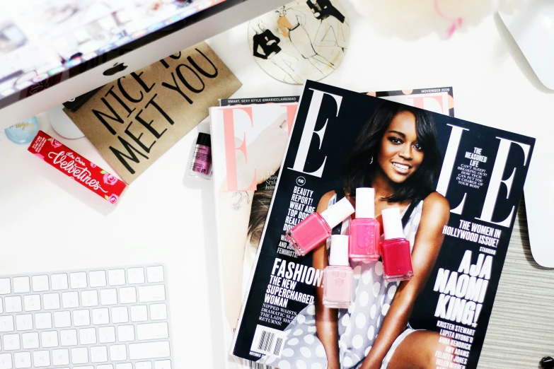 a person's nails on top of a magazine sitting on a desk