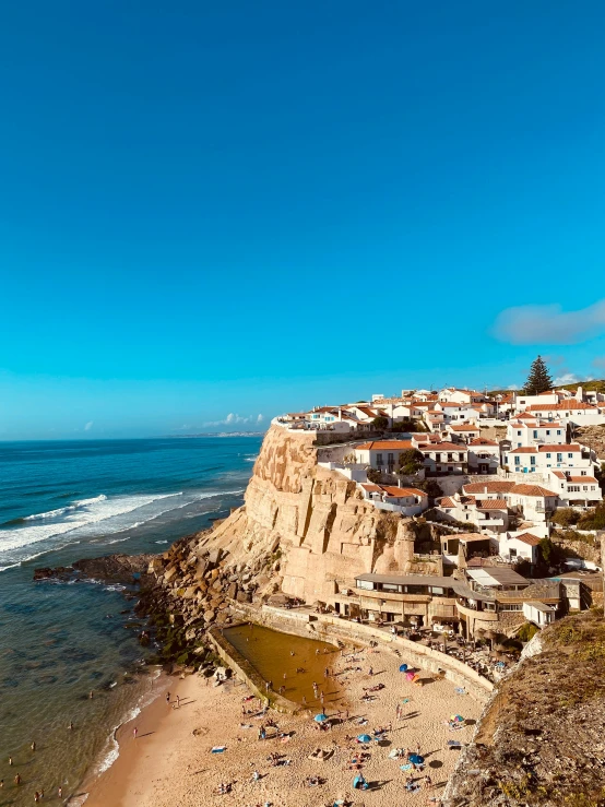 a scenic beach with swimmers on it under a blue sky