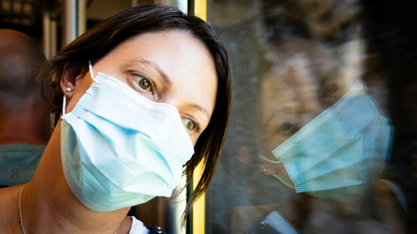 the lady wearing a face mask looks at the window