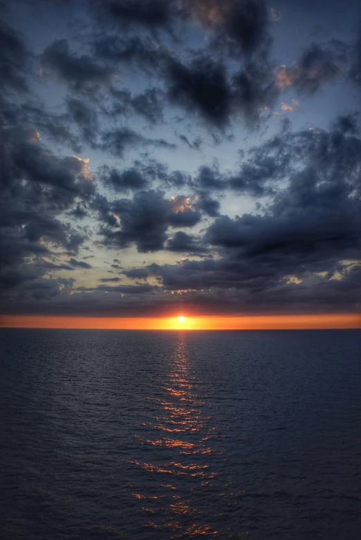 the sun shining through clouds over the ocean