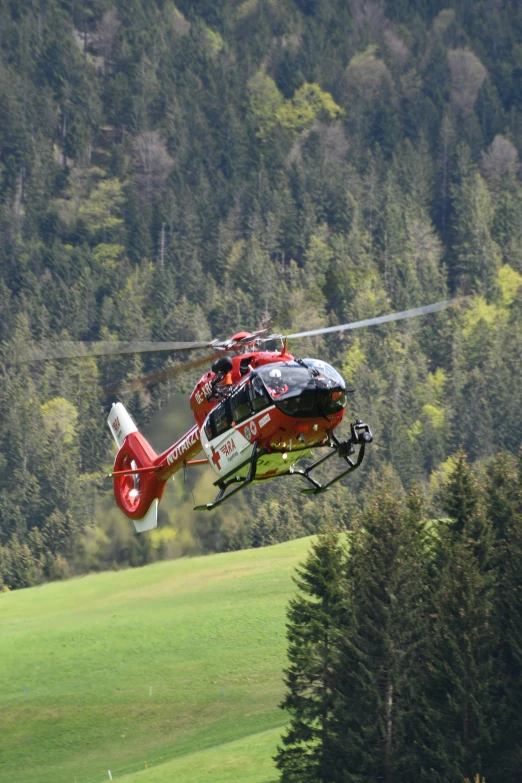 red helicopter in air with open wing taking off