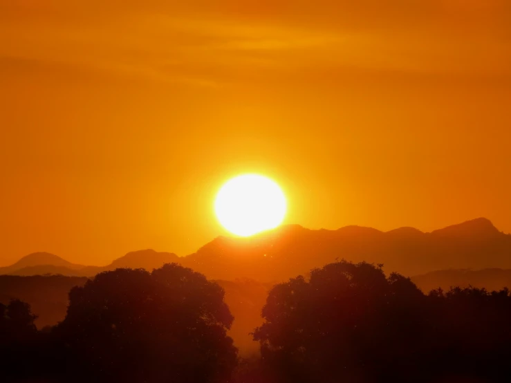 the sun is setting over mountains in the horizon