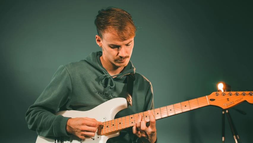 the young man is playing his guitar with the light on