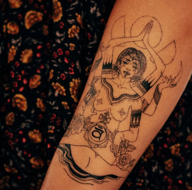 a black and white tattoo shows a woman's arms