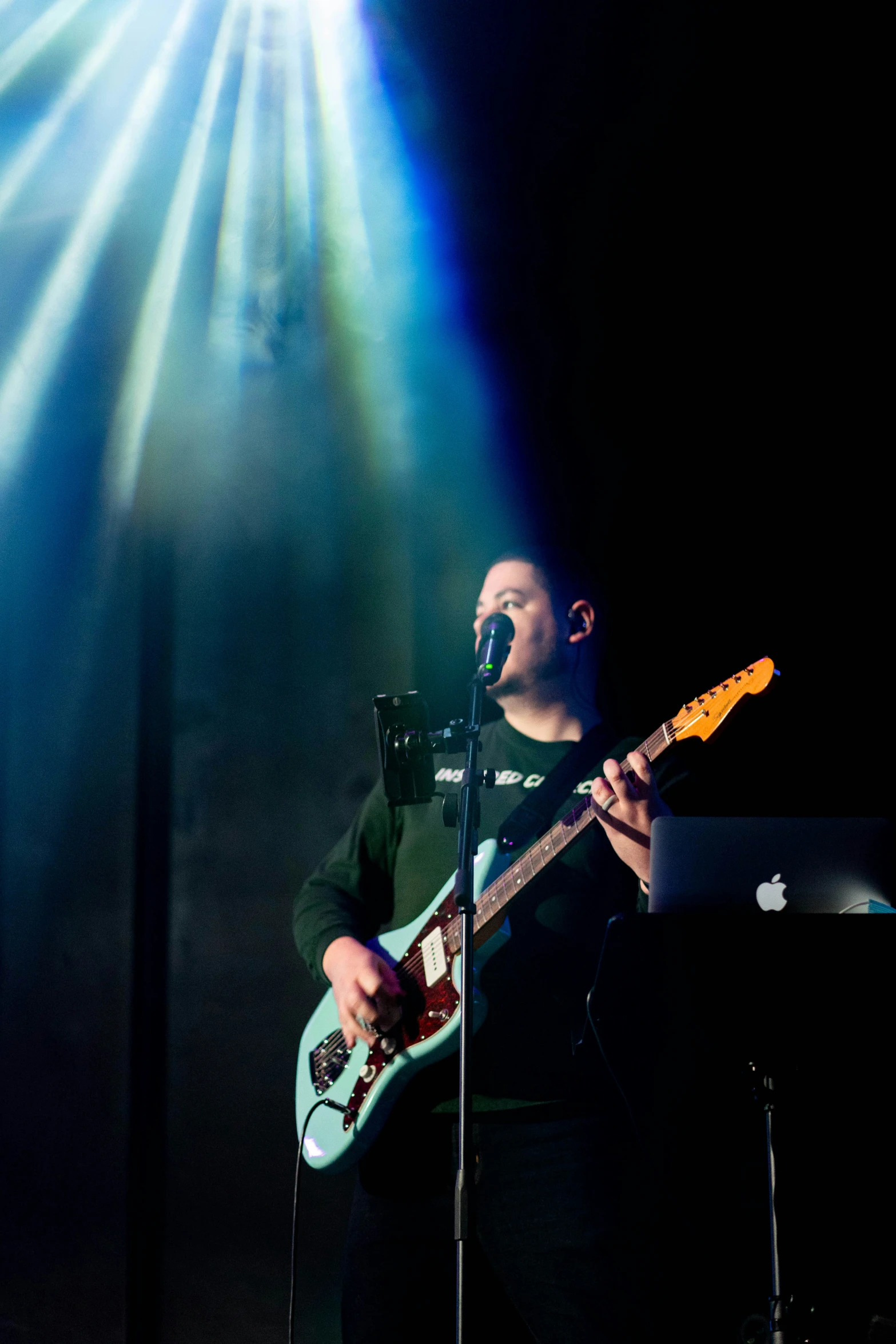 a male musician on stage singing into microphone and lighting