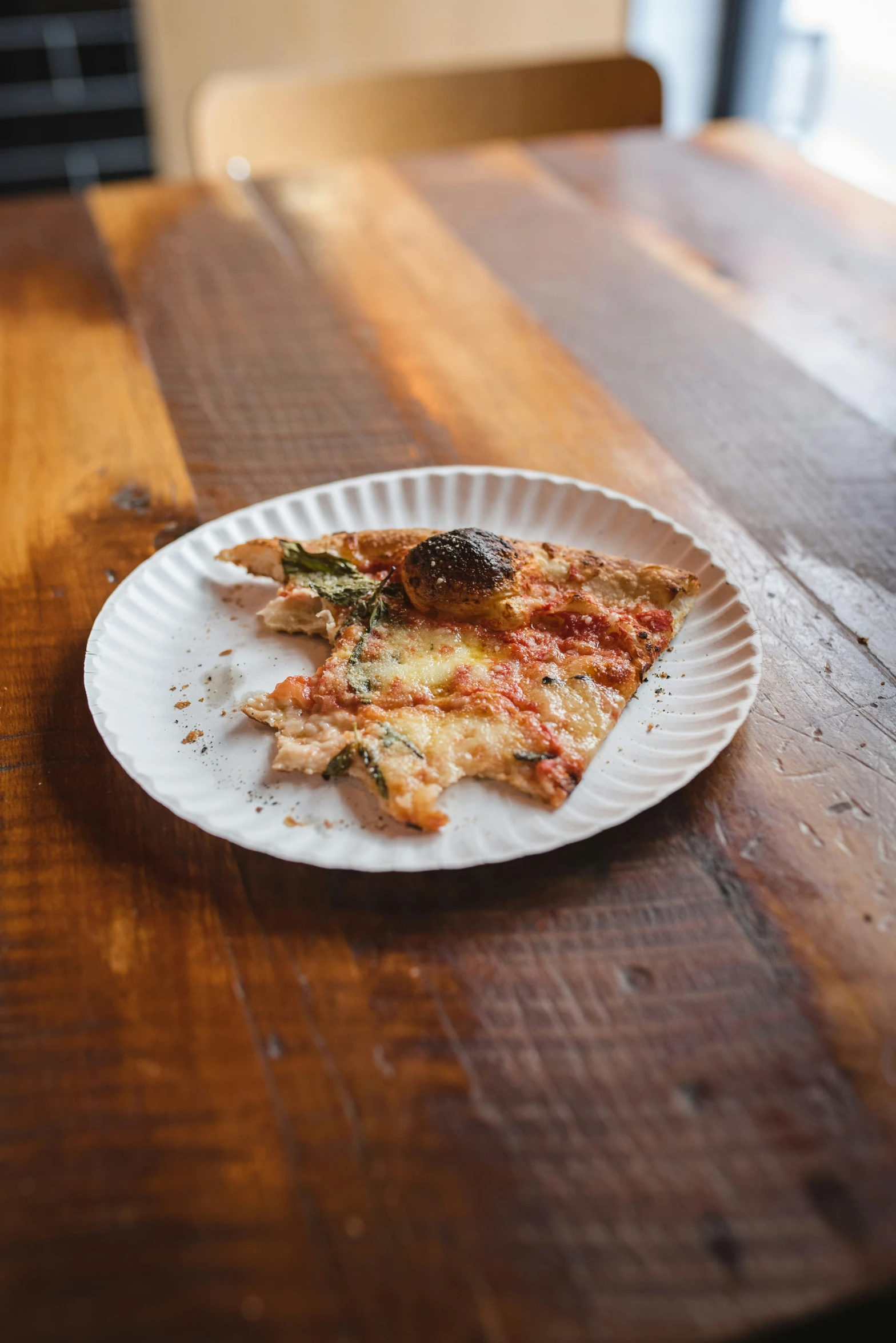 plate on wooden table with piece of pizza missing