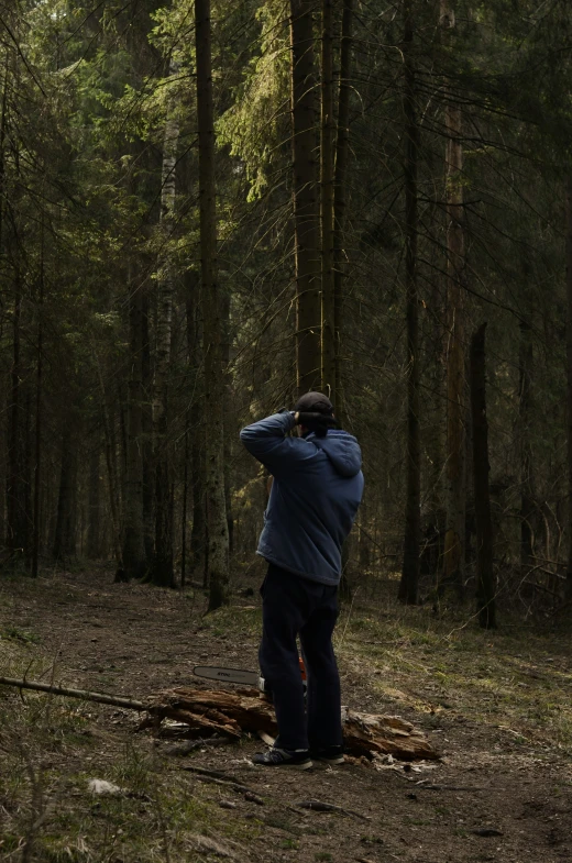 man standing in the middle of a forest, observing the tall trees