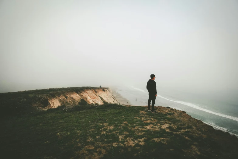 a person standing on a mountain top with a hazy sky