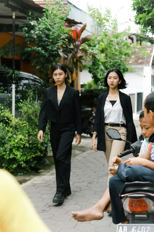 three women walking down the street and a man in a suit talking on his cell phone