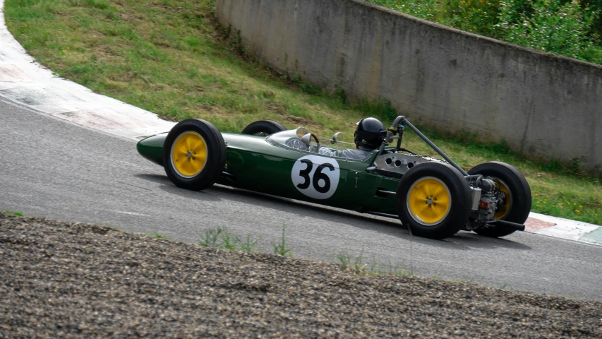 an older racing car drives on a road