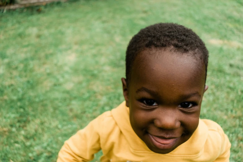 the young child is wearing a yellow shirt and smiling