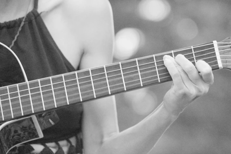 woman holding up her guitar looking at the strings