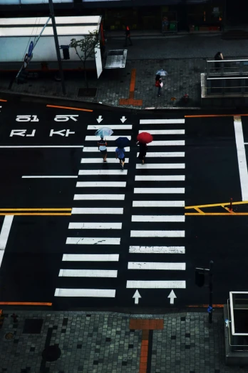 an aerial po of people with umbrellas crossing a street