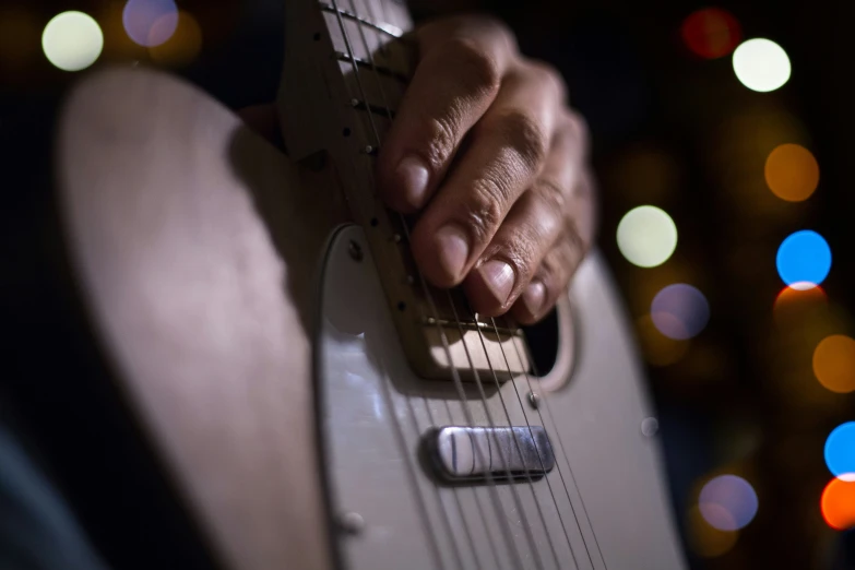 person holding onto their electric guitar in front of colorful lights