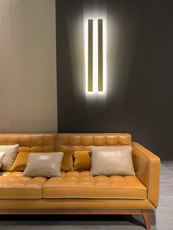 a couch with many pillows sitting next to a light