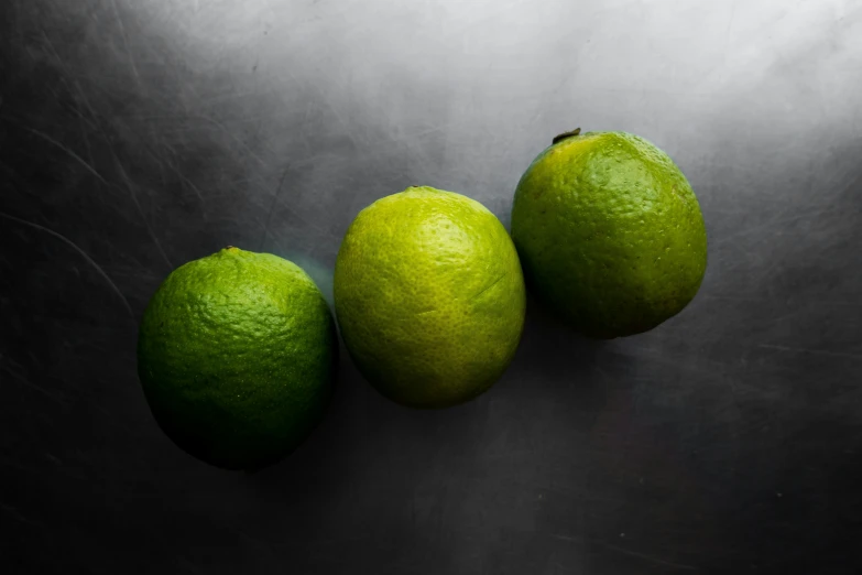 three limes sitting side by side on top of a counter