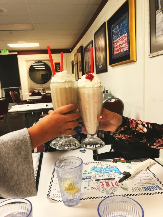 two people are toasting up two beverages on a table