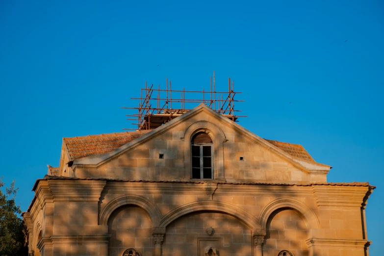 a church with scaffoldings on the roof and scaffolded against a blue sky