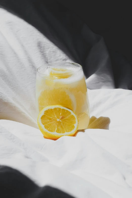 a glass filled with liquid next to a sliced orange