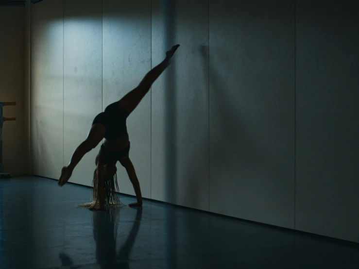 a person doing a back stand on one foot in a darkened room