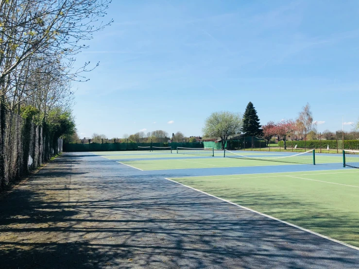 a tennis court with several tennis courts near the grass