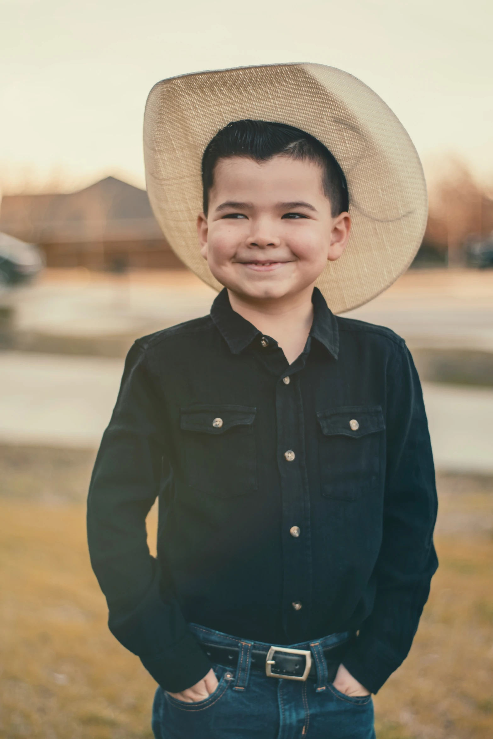 a little boy wearing a hat standing in the grass