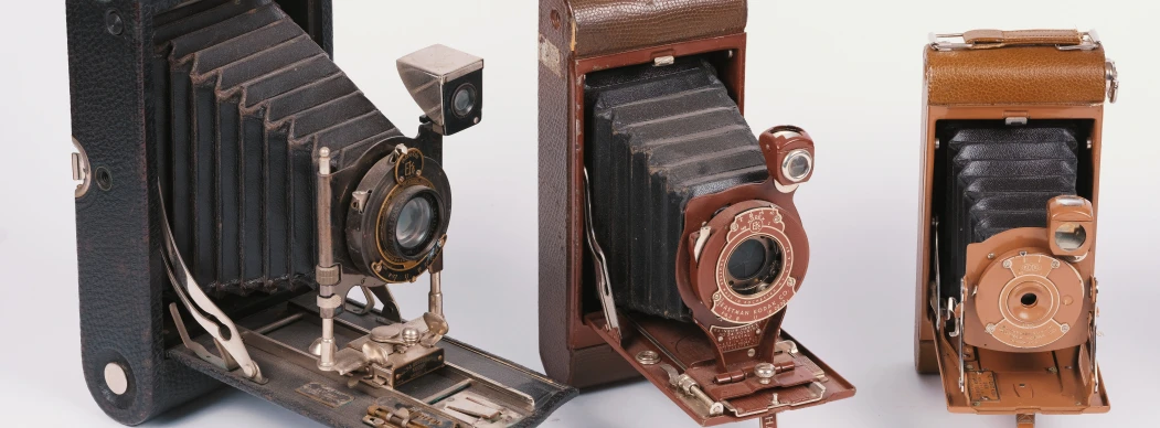 three old fashioned camera that are not in their housing