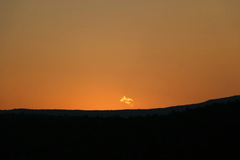 a silhouette view of a mountain with a sun setting