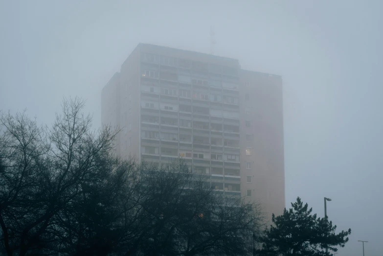 a very tall building with lots of windows in the fog
