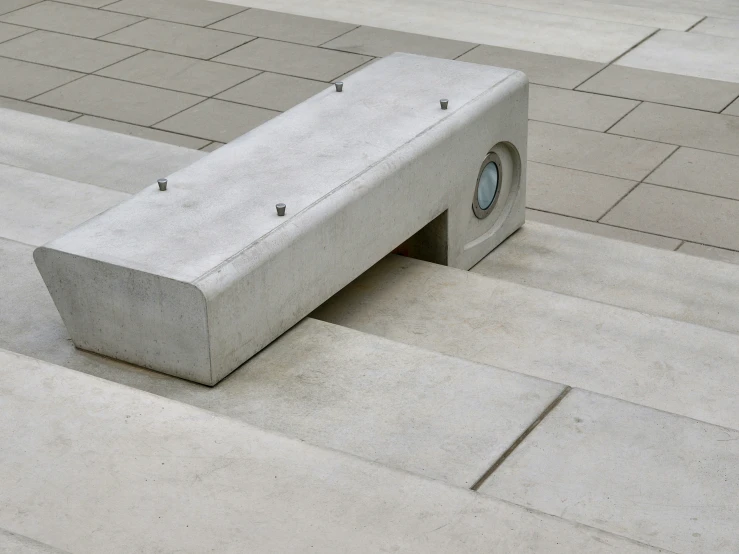 concrete bench sitting next to two matching gray tiles