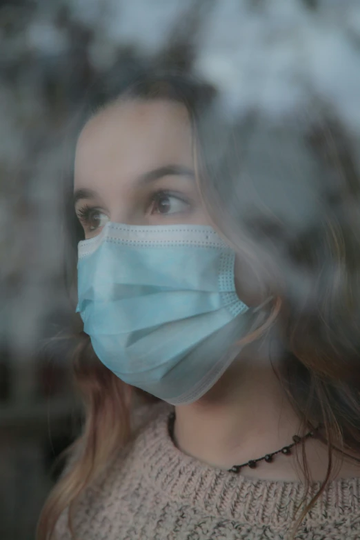 a woman with a face mask looking out the window