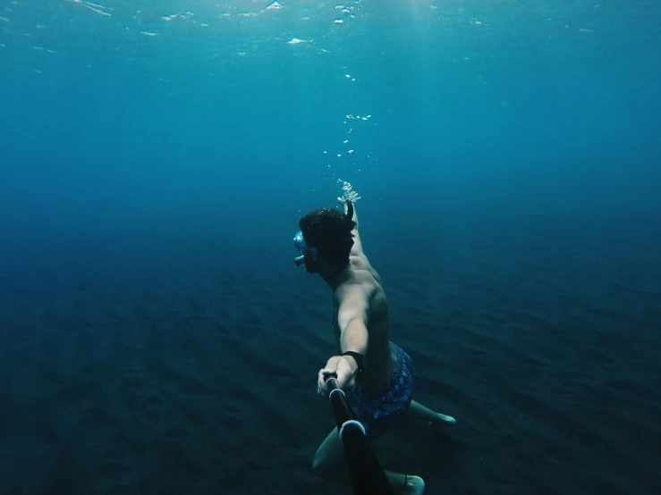 man diving under water with camera in hand