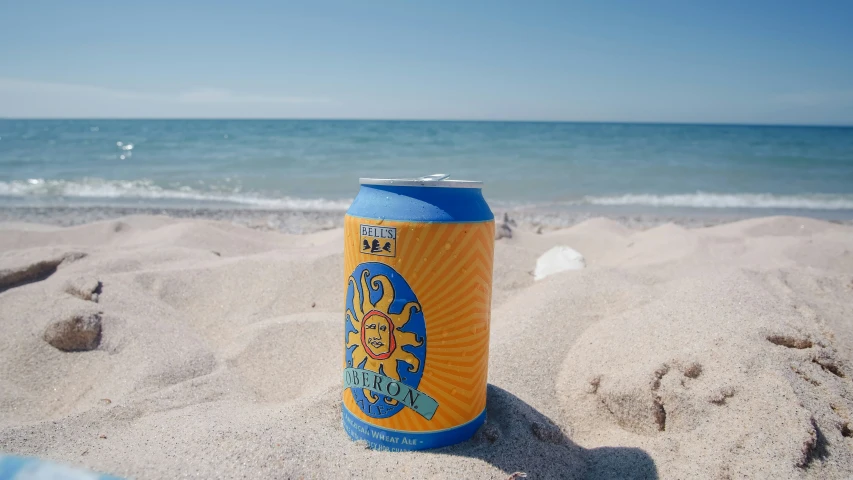 a can of beer is sitting in the sand near the ocean