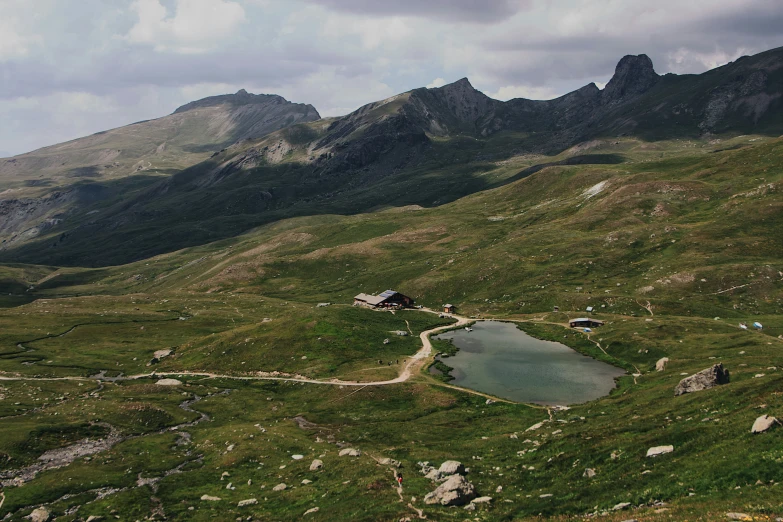 there is a pond at the foot of a grassy hill