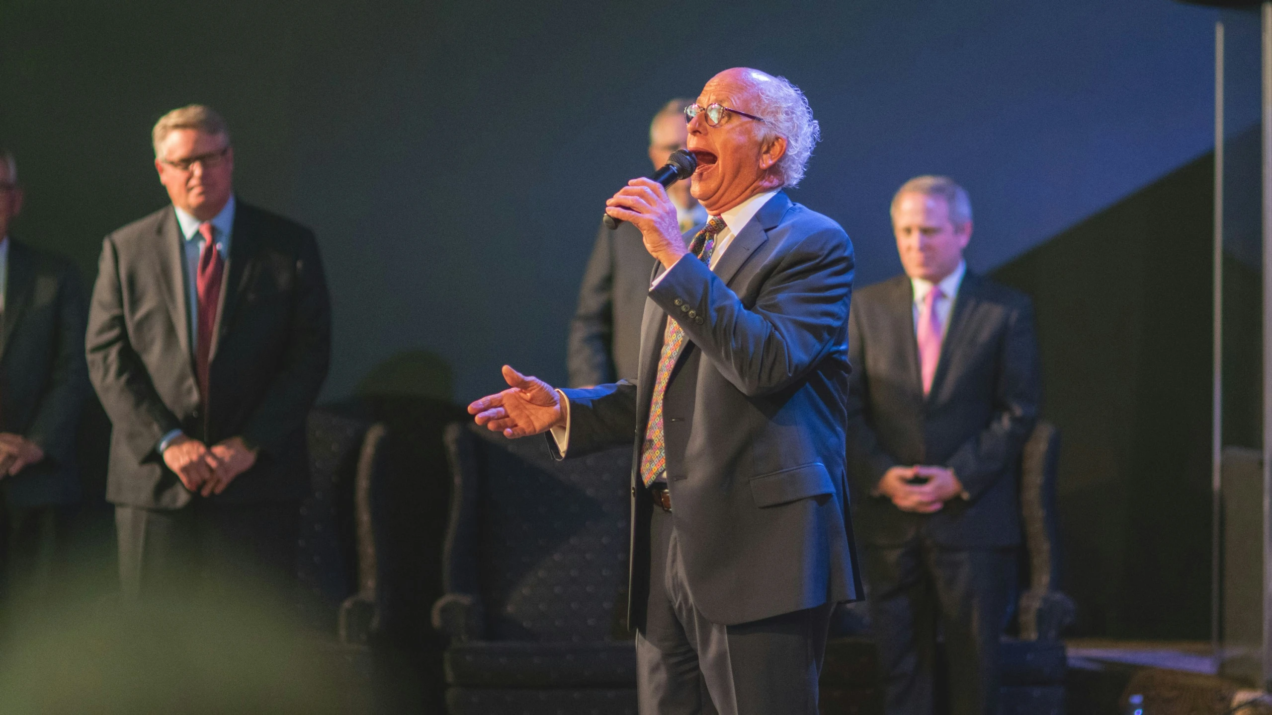 an older gentleman standing with his microphone up in the air