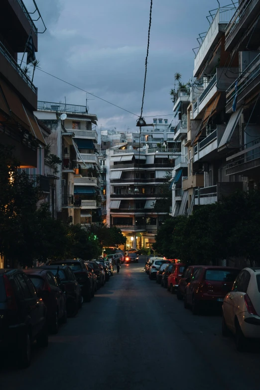 street lined with parked cars and tall buildings at dusk