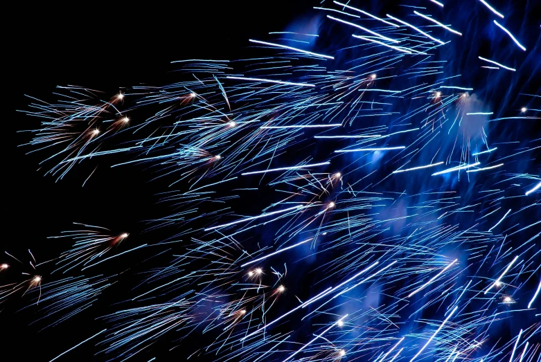 a bunch of blue and white fireworks in the night sky