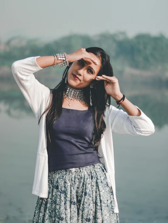 a woman wearing jewelry and posing with her hands in the air