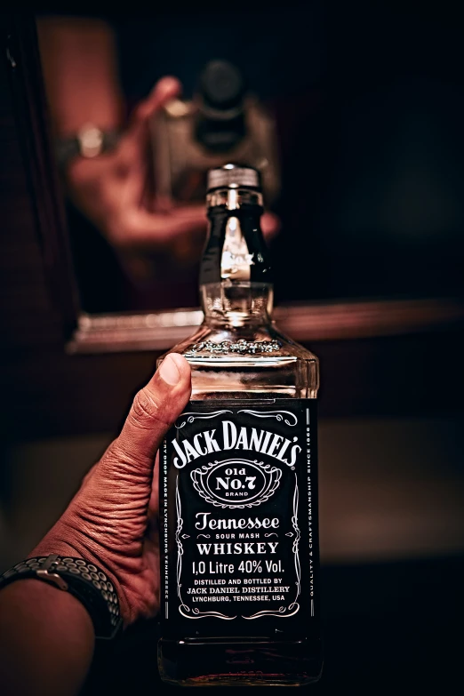 a hand holding a bottle of liquor in a dark room