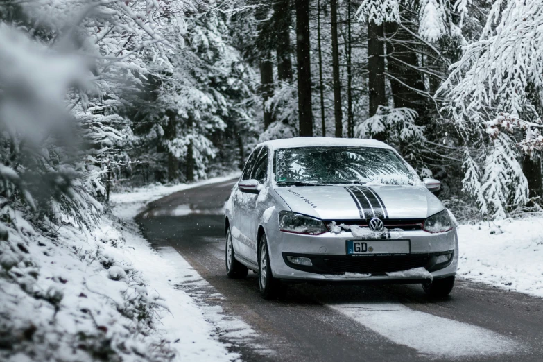 a car driving on a snowy road in the woods