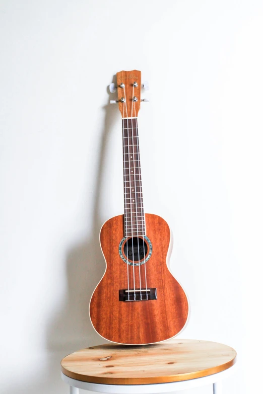 a small wooden ukulele is sitting on a stool