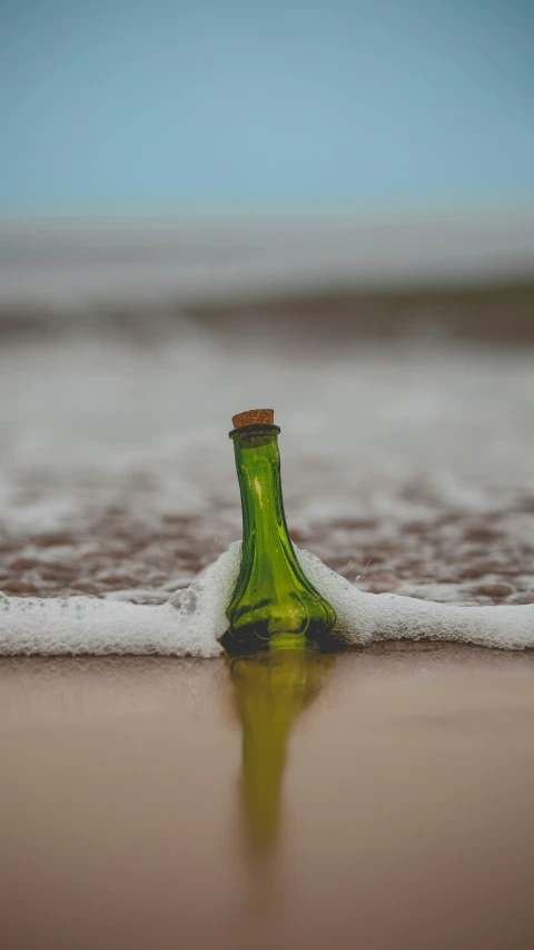 the bottle is sitting in the shallow water on the beach