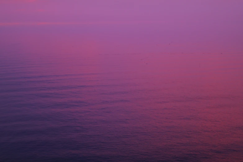 the sky is very purple as it sits on calm water