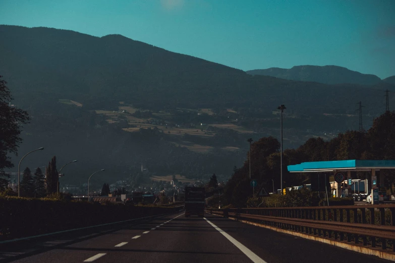 an empty highway at night with a gas station and mountain in the background