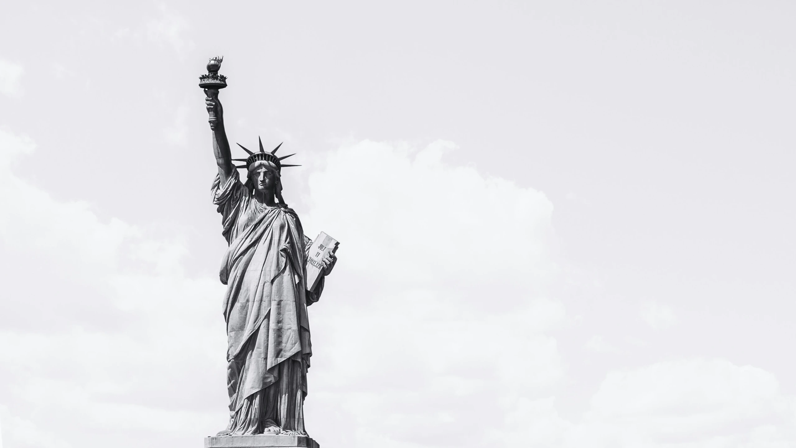 the statue of liberty is silhouetted against a cloudy sky