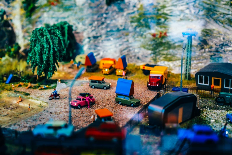 several toy vehicles, people and trees in the background