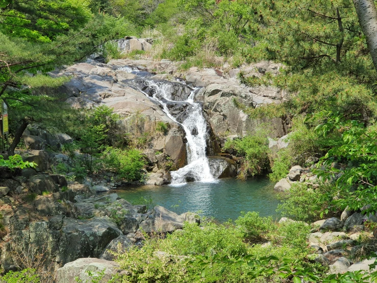 small waterfall at the bottom of a large cliff