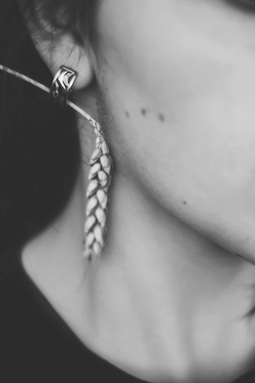 black and white po of woman's ear wearing a leaf - shaped earrings